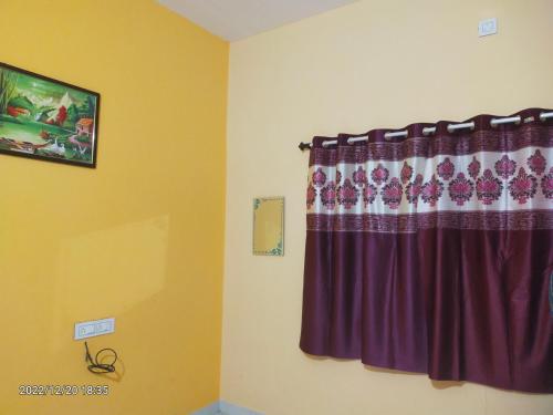 una camera con finestra con tenda viola di Saurabh Guest House, Akkalkot a Akalkot