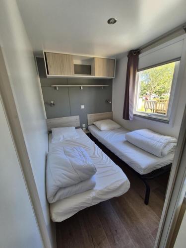 deux lits dans une petite pièce avec une fenêtre dans l'établissement camping la plage de l'orb, à Cessenon