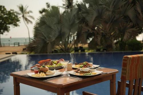 a table with plates of food on it next to a pool at Hibiscus Beach Hotel & Villas in Kalutara