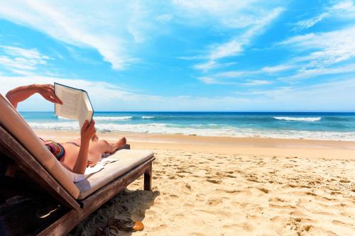 a woman laying on a beach reading a book at Caorle Oasis Beach House - Host Solution in Caorle