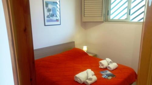 Un dormitorio con una cama roja con toallas. en Bilocale Delle Robinie in Baia Verde, en Baia Verde