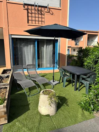 une table, des chaises et un parasol sur l'herbe dans l'établissement Studio agréable de 21m2, à Balaruc-les-Bains