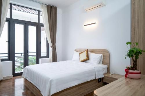a bedroom with a white bed and a large window at DELUXE VILLA 2 có 5 phòng ngủ trung tâm tp in Thôn Trường Giang