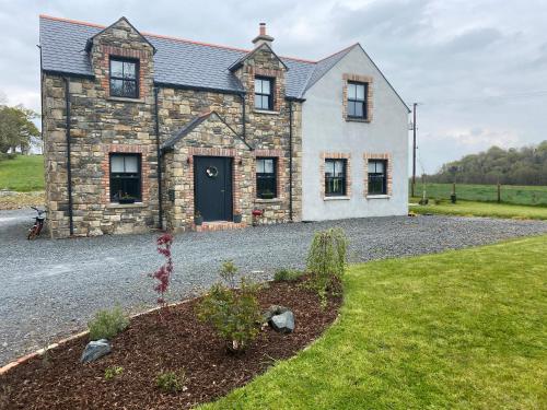 a stone house with a gravel driveway at Maggies Cottage in Belturbet