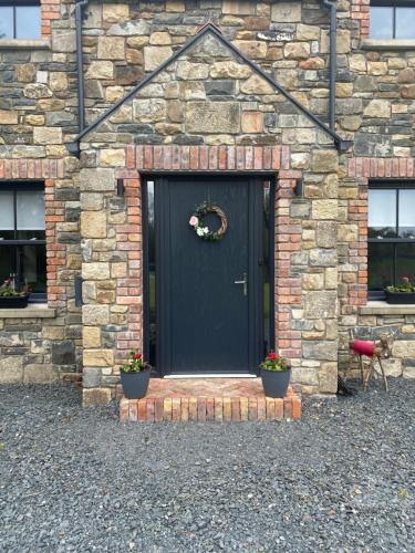 a black door of a stone building with two potted plants at Maggies Cottage in Belturbet