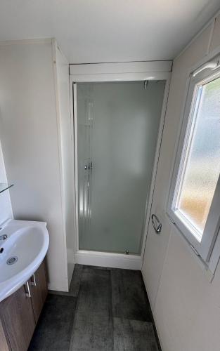 une salle de bain avec une douche et un lavabo et une fenêtre dans l'établissement camping la plage de l'orb, à Cessenon