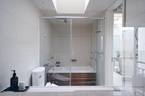 a bathroom with a glass shower and a tub at Chulin Homestay in Tainan