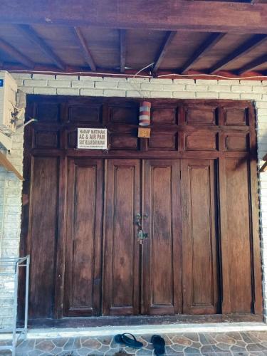 una puerta de madera de un edificio con un cartel en Jimbaran homestay, en Mantaak