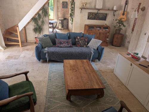 un salon avec un canapé bleu et une table basse dans l'établissement Maison au bord d'un ruisseau, à Pontigné