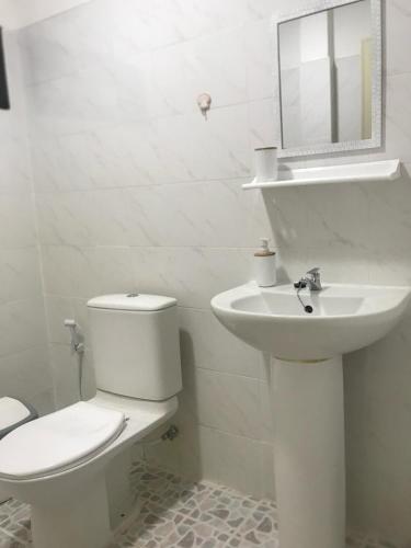 a white bathroom with a toilet and a sink at Chiltern cottages in Amphoe Koh Samui