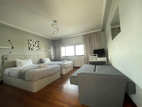 a bedroom with two beds and a couch at Surf & Guest Lorena´s House in Ribeira Grande