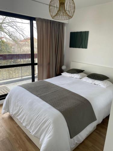 une chambre avec un grand lit avec une grande fenêtre dans l'établissement Beautiful comfortable apartment, à Talence