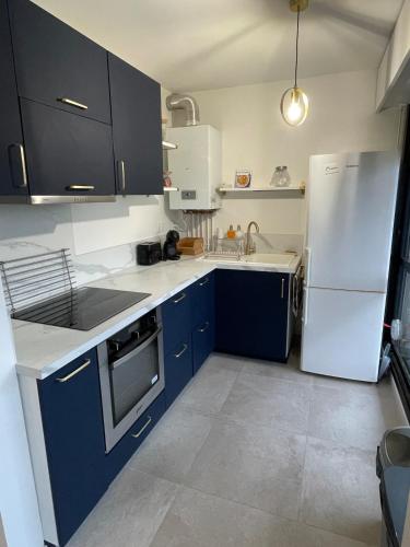 une cuisine avec des armoires bleues et un réfrigérateur blanc dans l'établissement Beautiful comfortable apartment, à Talence