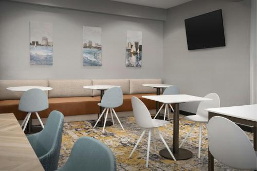 a waiting room with tables and chairs and a tv at TownePlace Suites Suffolk Chesapeake in Suffolk