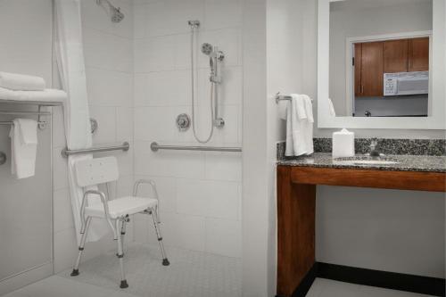 a bathroom with a shower with a chair and a sink at TownePlace Suites Suffolk Chesapeake in Suffolk