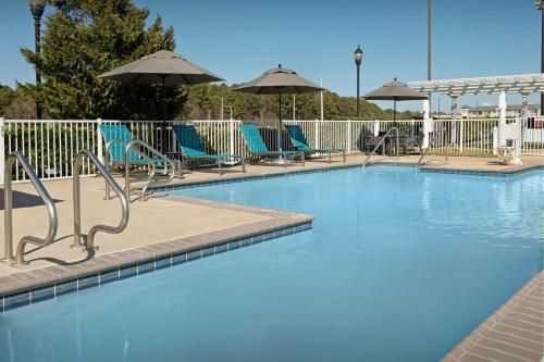 a large swimming pool with chairs and umbrellas at TownePlace Suites Suffolk Chesapeake in Suffolk