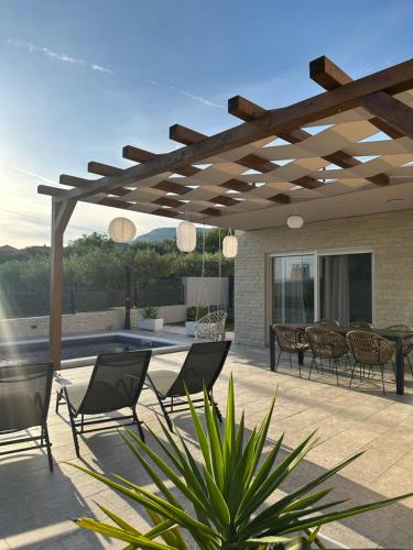 eine Terrasse mit Stühlen und einer hölzernen Pergola in der Unterkunft Villa Teuta in Kaštel Stari