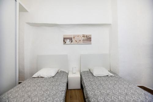 deux lits dans une chambre aux murs blancs dans l'établissement Grand appartement, plein centre, à La Ciotat
