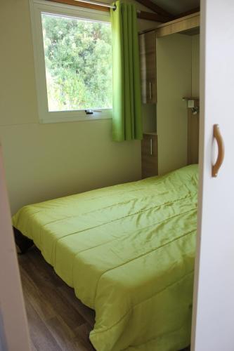 - une chambre avec un lit vert et une fenêtre dans l'établissement Les Hauts de Torraccia, à Cargèse