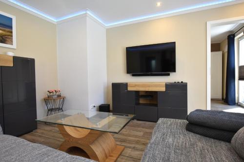 a living room with a glass coffee table and a tv at Bungalow Achtern Huus in Grube