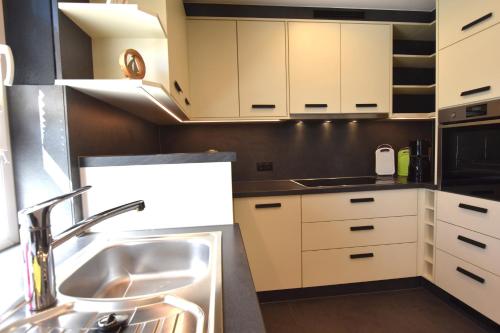 a kitchen with white cabinets and a sink at Bungalow Achtern Huus in Grube