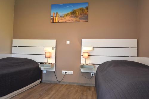 a bedroom with two beds and two lights on the wall at Bungalow Achtern Huus in Grube