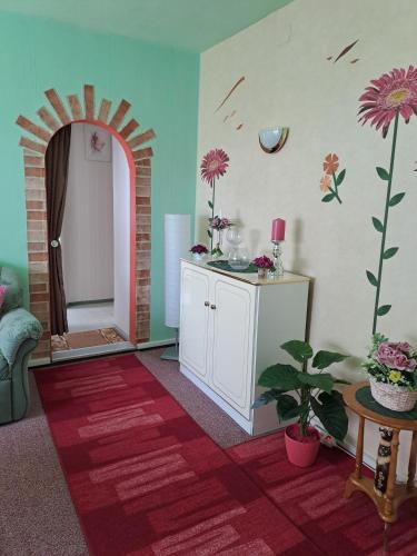 a room with a table and a room with flowers on the wall at Pension Kaufmann Ferienwohnung "Wolke 7" in Oberwiesenthal