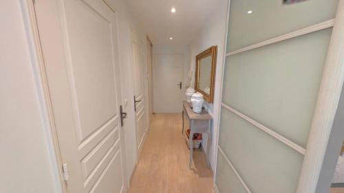 un couloir avec une porte blanche et un miroir dans l'établissement Appartement avec terrasse au coeur de la nature, à Annonay