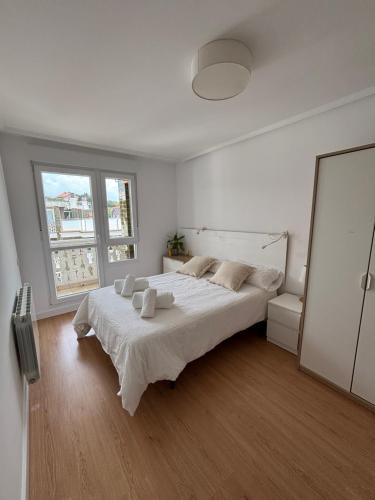 a white bedroom with a large bed and a window at Casa Mouro Somo - Surf y playa in Somo