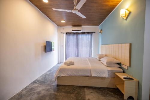 a bedroom with a bed and a ceiling fan at Bibee Surf in Thulusdhoo