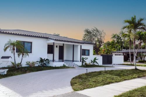 a white house with palm trees and a driveway at Miami Freedom Park Oasis by H&S in Miami