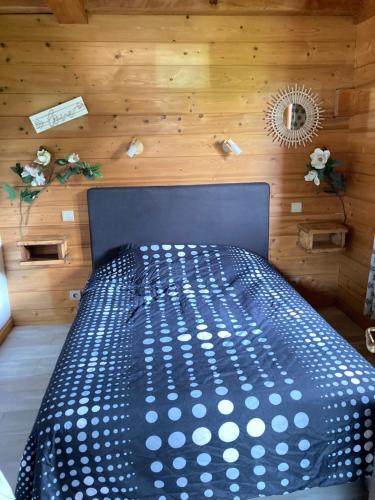 - un lit noir dans une chambre dotée d'un mur en bois dans l'établissement Chalet Cosy avec terrasse plein sud, 2 chambres, au cœur de la Haute-Savoie, à Châtillon-sur-Cluses