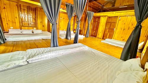 Habitación con 2 camas, suelo de madera y paredes de madera. en Nàng Ban house, en Mộc Châu