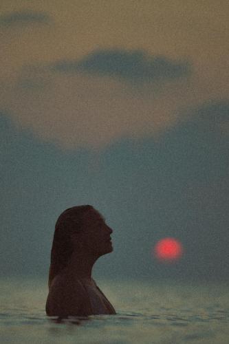 a silhouette of a person in the water at sunset at Bibee Surf in Thulusdhoo