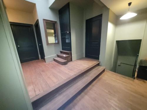 an empty room with two stairs and two black doors at Maison d'hôtes Coeurdacier in Monthureux-sur-Saône