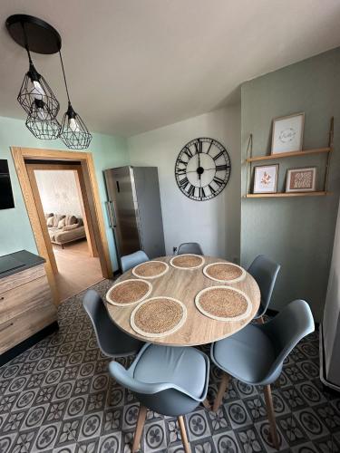 a dining room table with chairs and a clock on the wall at Bel appartement F4 6 a 7 personnes in Lutterbach