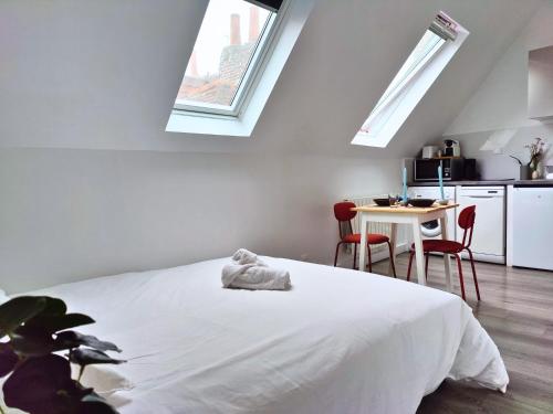 Cet appartement comprend une chambre avec un lit et une cuisine dotée de lucarnes. dans l'établissement Studio passage des arts - Vieux Lille, à Lille
