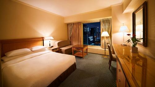 a hotel room with a bed and a desk and a window at RIHGA Royal Hotel Osaka, Vignette Collection by IHG in Osaka
