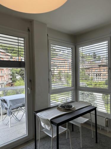 a dining room with a table and two windows at Free Parking - Near the Lake - Lugano apartment in Paradiso
