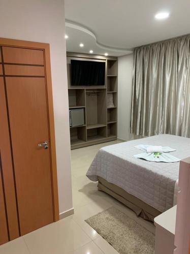 a bedroom with a bed and a tv and a door at Prudentópolis Palace Hotel in Prudentópolis