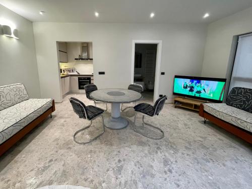 een woonkamer met een tafel en stoelen en een televisie bij Glass & Charme - Central Suite in Turijn
