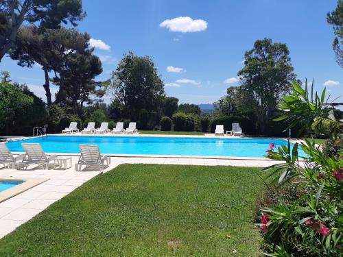 une grande piscine avec des chaises et une pelouse dans l'établissement Appartement Aix, résidence calme avec piscine, à Aix-en-Provence