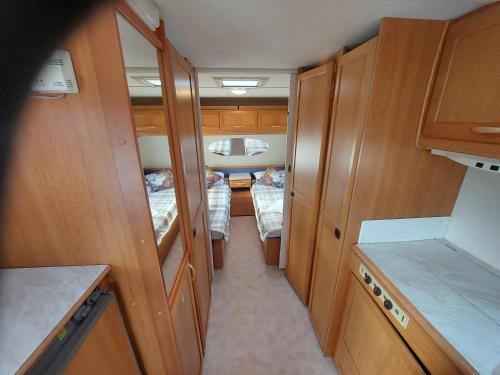 a small kitchen with wooden cabinets and two beds at Halfway in Kabelvåg
