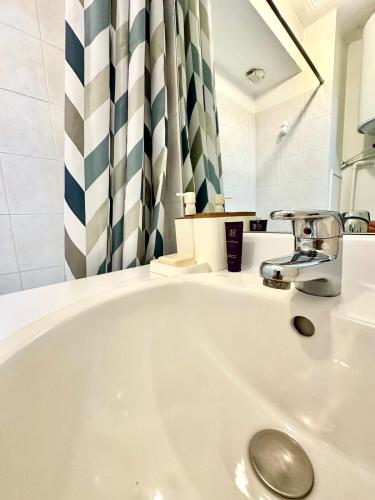 La salle de bains blanche est pourvue d'un lavabo et d'un robinet. dans l'établissement La Suite Bellecombe, à Lyon