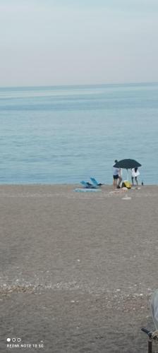 a group of people under an umbrella on the beach at vacanza Taormina mare in Mazzeo