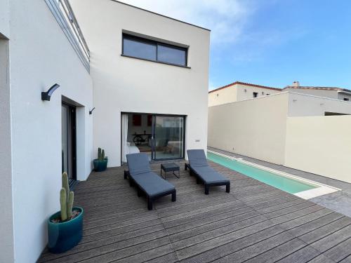 une terrasse avec des chaises et une piscine dans une maison dans l'établissement Villa d'architecte, à Port-la-Nouvelle