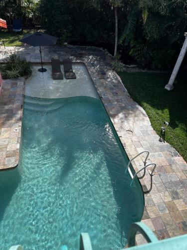 a pool of water with an umbrella in a yard at Tree Top Retreat! Private & close to 5th Ave! in Naples