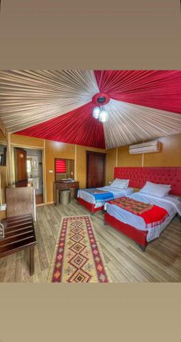 two beds in a room with a red ceiling at Maha Wadi Rum in Wadi Rum
