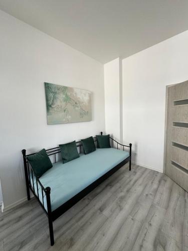 a bed with green pillows in a white room at Masarykova apartments in Teplice