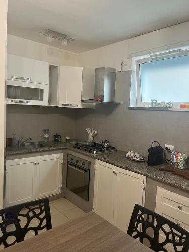 a kitchen with white cabinets and a sink and a window at Dimora Dune in Campomarino